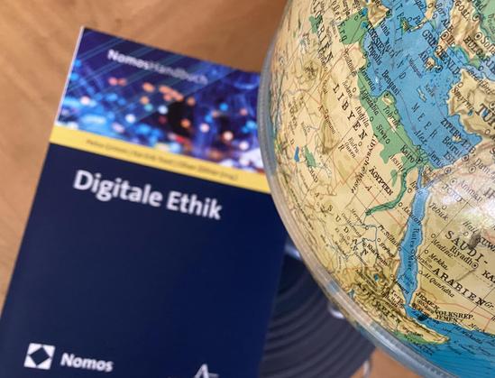 Das Handbuch "Digitale Ethik" und ein Globus.