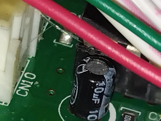 A tubular 10uF capacitor soldered closely to a circuit board. There seems little chance of replacing it without getting to the other side of the board.
And that requires disassembly of the board from the display screen.