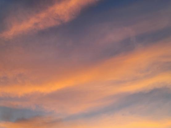 diagonal striations of sunset-lit clouds and still-blue evening sky