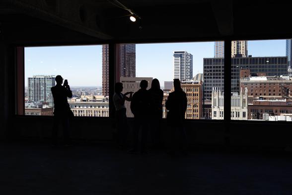 Visitors take in the view from the vacant and stripped-bare 19th floor of 333 S. Wabash.
People are silhouetted against the win.dows, through which a view of downtown Chicago is visible