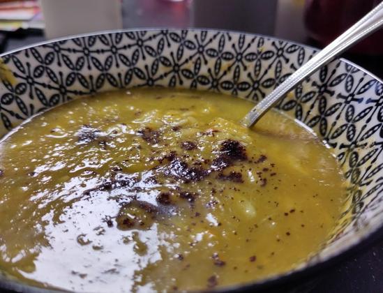 Suppe in der Suppenschüssel mit Löffel drin.