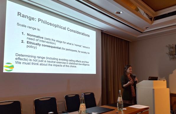 Speaker at a lectern in front of a screen showing a slide with the title "Range: Philosophical Considerations"

Scale range is:
Normative (sets the stage for what is “normal,” versus in need of intervention)
Ethically consequential (for participants, for society, for policy)

Determining range (including avoiding ceiling effects and floor effects) is not just a neutral exercise in statistical due-diligence. We must think about the impacts of this choice.