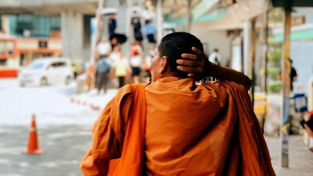 Buddhist monastic walking on city street.