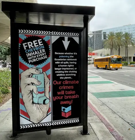 Text:
Free CHEVRON inhaler with every purchase.

Because whether its poisoning the Ecuadorian rainforests with. Oil spills, having a human rights lawyer imprisoned, or creating the choking wildfires scorching the planet …

OUR CLIMATE CRIMES 
WILL TAKE YOUR BREATH AWAY

Image:
 a hand holds an asthma inhaler labelled CHEVRON
Poster is under glass inside an advertising space on a bus shelter in a public street. 

Art by https://www.frankriot.co.uk/about-3