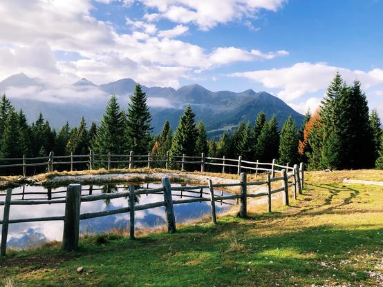 A reservoir surrounded by a fence and mountain peaks in the distance