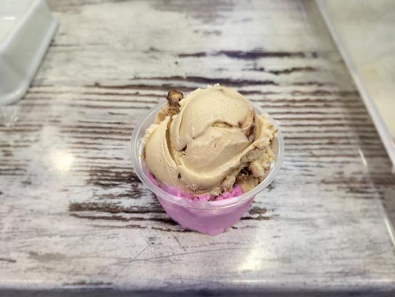 Cup of ice cream, yellow-white (Bueno) and red (strawberry), on a somewhat white painted wooden table