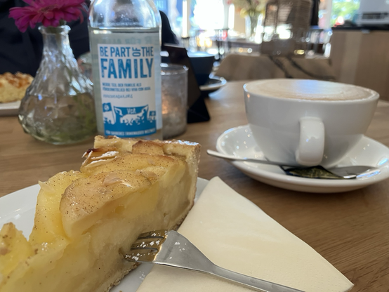 Lecker Apfelkuchen mit Milchkaffee, Flasche Wasser auf einem Tisch stehend