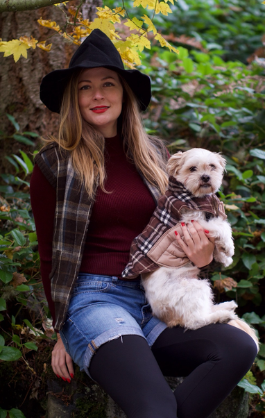 Picture of a good witch in plaid and her dog in matching plaid with Fall foliage in the background. 