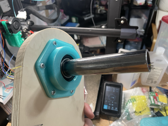 A steel shaft mounted inside a bearing, mounted inside a 3D printed housing, attached to a custom cut plywood pillar. 