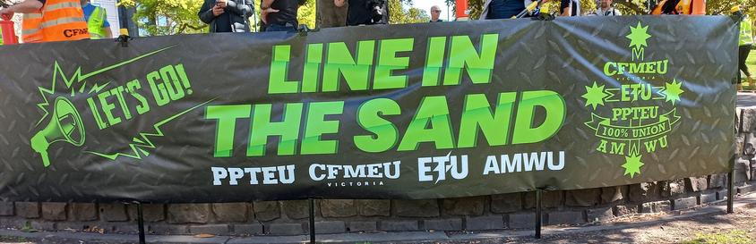 “Text on banner:

Let’s GO 

LINE IN THE SAND

CFMEU 
PPTEU 
AMWU 
ETU 