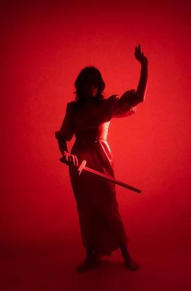 Blindfolded Lady Justice holding up one hand with a sword in her other hand