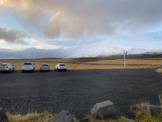 View over the parking lot, in the background snow covered hills. Cloudy sky. 
