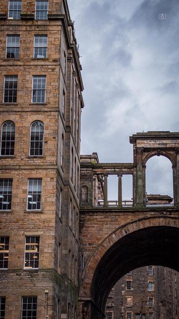 Cloudy skies above a stone bridge and tall building. Regent Bridge, Edinburgh, 19 Aug 2024. Nikon D5600, Nikkor DX 35 mm ƒ1.8G, ISO 640, ƒ4, -0.3 ev, 1/2500s, polarizing filter