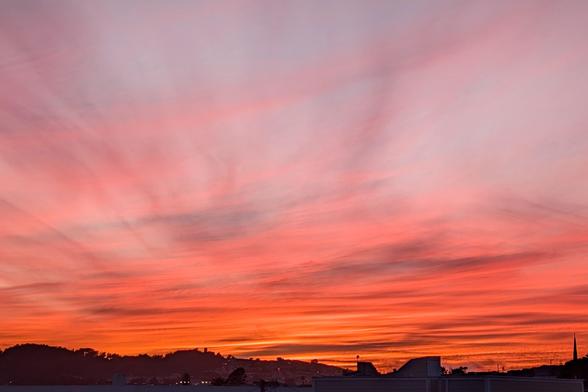 Photograph of a smoldering sunset over the Bayview in San Francisco. Intense corals and oranges with streaks of gold and deep amethyst.