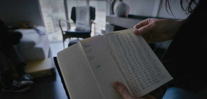 A photograph of an open notebook. On one page it says "Here we go" and on another page the words "I will sell out the Roger Center" are written on every line of the page.