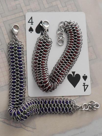 the same two bracelet as the previous image, though one  is lying on a four of spades playing card as a size reference.
