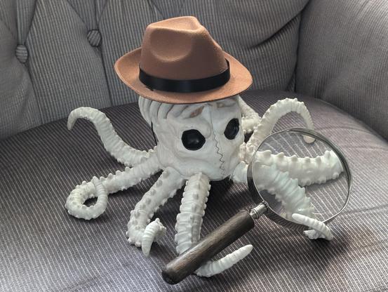 Octopus skeleton Halloween decoration sitting on old chair wearing a fedora and holding a magnifying glass
