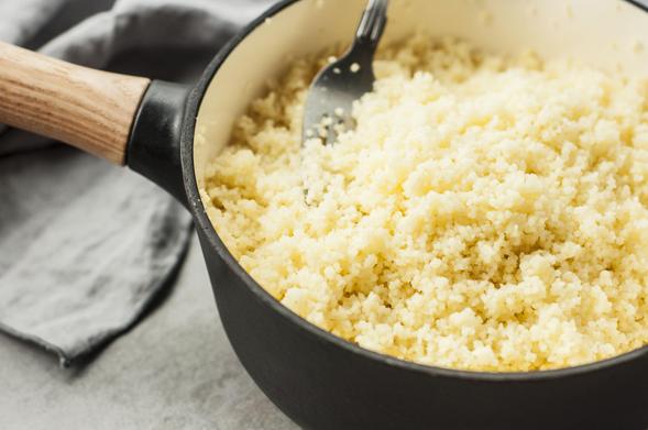 Preparing couscous in a skillet, fluffing it with a fork.