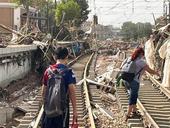 Photographs of the floods in Spain: A woman and a child walk along a railroad track