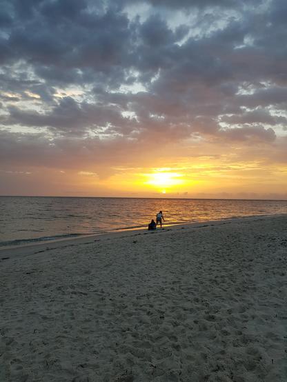 Sonnenaufgang am Strand von Sousse in Tunesien. Vorne am Wasser sind die Konturen von zwei Personen zu sehen.