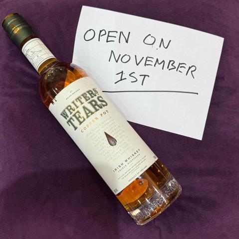 A bottle of Writers Tears Irish whiskey next to a note saying "Open on November 1st"