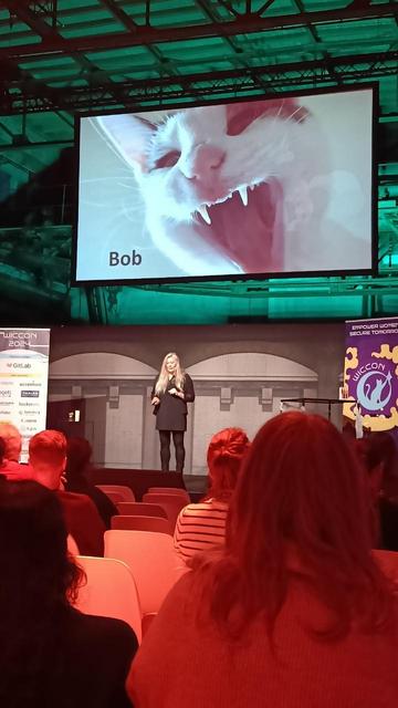 Helma on stage at Wiccon with a picture of Bob, a black and white cat.