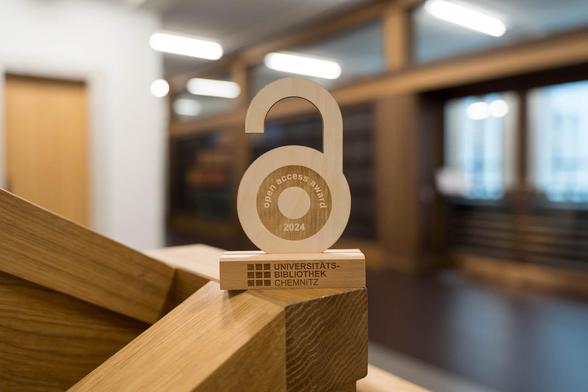 Deutsch: Es ist der Open Access Award der Universitätsbibliothek der TU Chemnitz zu sehen. Er ist in der Form des Open Access Logos gestaltet und aus Holz gefertigt.

English: The Open Access Award of the Chemnitz University of Technology Library can be seen. It is designed in the shape of the Open Access logo and made of wood.