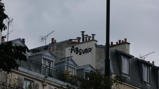 Photo by Fenichel: 
Rooftops in Paris, attic windows and chimney smokestacks.
On a small white-painted wall beneath the chimneys, is the word:
"ABSURD"