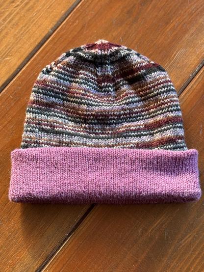 Green, brown, purple and light purple striped hat with the purple inside folded out so it has a purple brim