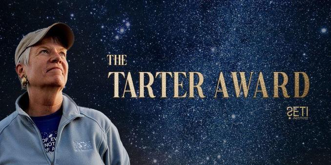 Starry background with a thick band of stars going from near the right edge to just over halfway across. Text: The Tarter Award, done in a golden font. Gold SETI Institute logo just below. On the left, a cut out picture of Jill Tarter, gazing up and to the right, wearing a SETI Institute fleece over a t-shirt, chunky gold earrings, and a tan baseball hat. She appears to be smiling at the stars.