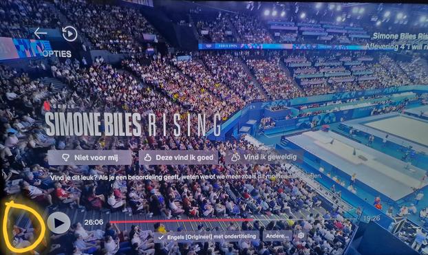 Foto van de Bercy Arena in Parijs met een  oranje cirkel linksonder getekend om Helma, net te herkennen aan oranje hemdje dat ze vasthoudt en de zwarte korter broek. Je ziet rijden én rijden van de tribune, wel zo'n 15 en rechts in beeld zie je een deel van de turnapparaten (balk en vloer).