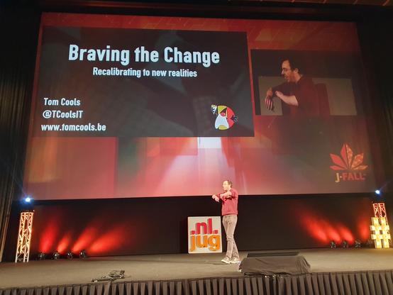 Tom Cools on the JFall stage. The slide says Braving the Change.