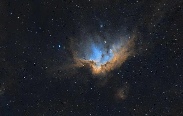 NGC 7380: Wizard Nebula
Black background with many stars of varying brightness spread throughout.

At center is an area of nebulosity with a patch of orange running horizontally and highlighted by some blue nebulousness above middle.