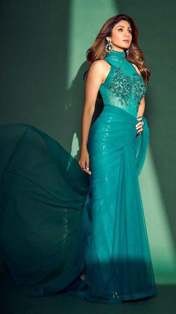 Embracing a mix of elegance and edge, Shilpa Shetty’s teal hybrid saree is a show-stopping masterpiece! The saree’s sleek drape paired with a striking statement blouse makes her look both timeless and on-trend. Perfect for any special occasion, this outfit reveals why Shilpa is always ahead in the fashion game. Get inspired by her effortless style and bold color choice!