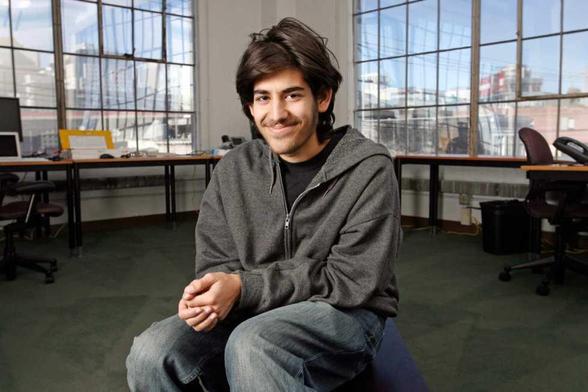 A photo of Aaron Swartz sitting down and smiling.