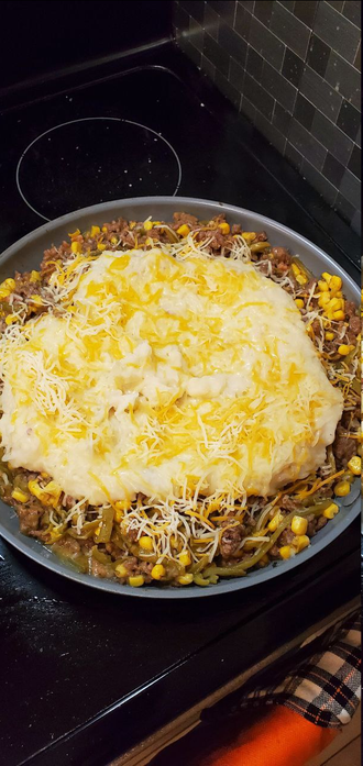 Picture of a pan filled with meat, veggies, mashed potatoes, and cheese