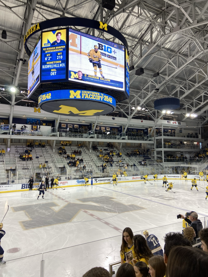 A hockey stadium with players in bright yellow warning up on the ice.
