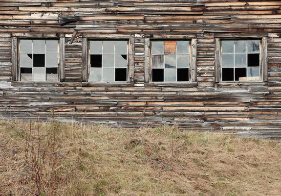 Four barn windows, each with a different pattern of broken panes.
