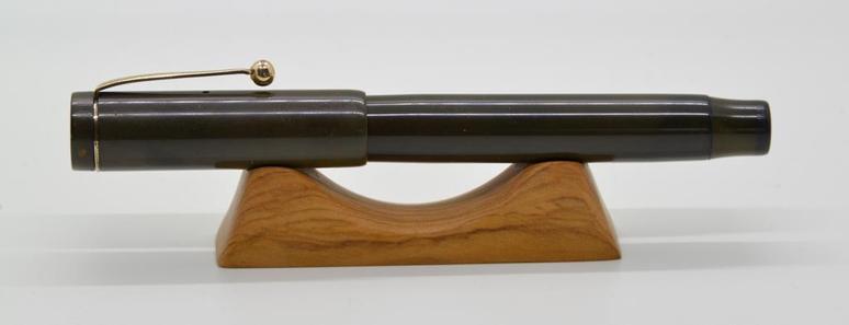 Closeup of a vintage fountain pen, capped, a lying on a pen cradle.
