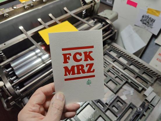 Foto Hand hält eine Karte mit dem Aufdruck FCK MRZ