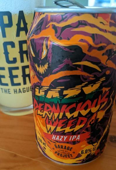 Close-up of a can of Pernicious Weed hazy IPA by Garage Project. Glass next to it, slightly in the back.