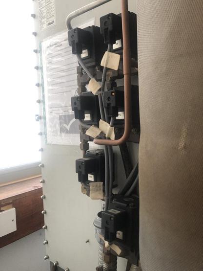The solenoid valves and pipework on the side of an MBraun glove box with one light glowing . 