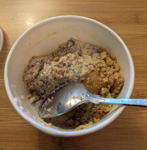 A paper bowl of... something? It looks like a generous helping of wholegrain porridge, with natural yoghurt, & topped with fruit crumble or granola. It's absolutely delicious!
