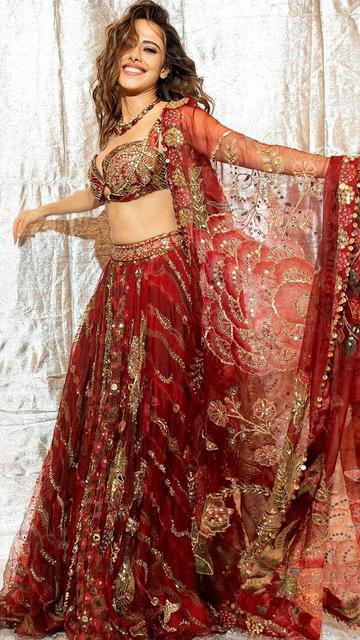 Dive into Nushrratt Bharuccha’s exquisite red lehenga that screams elegance and class. The intricate detailing and luxurious fabric make it a perfect choice for brides and fashion lovers alike. Get inspired to transform your festive wardrobe with this glamorous style.