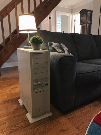 It's a couch side table (next to a couch) which looks like an old off white computer tower. I think it's probably (?) just a replica and not actually one, as it looks a little too thin and too tall to me, but who knows. It has slots for diskettes and a power button. A potted plant sits on top