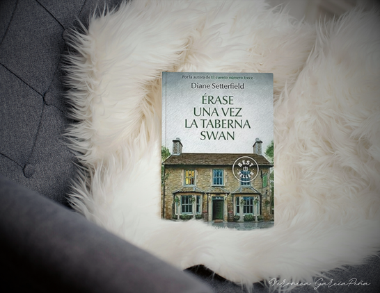 Portada del libro 'Érase una vez la taberna Swan' l, de Diane Setterfield, sobre una suave manta blanca. Imagen destacada de la reseña publicada en el blog literario 'El Jardín del Sur', dirigida por la escritora y periodista Verónica García-Peña."