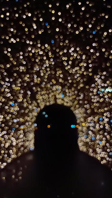 Noc. Złote, gęsto ułożone, eteryczne kółeczka światła, układające się w kształt bramy w postaci tunelu prowadzącego w ciemność.