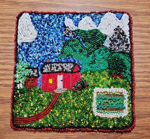 Red cabin and woodshed, yard full dandelions, small garden. Hills and trees and snow covered mountains.
