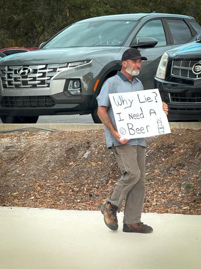 A #man with a #sign that says #why #lie? I #need a #beer. 