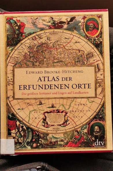 Cover des Buches, eine runde Landkarte umgeben von alten Zeitungen in bunt, in der Mitte der Titel
